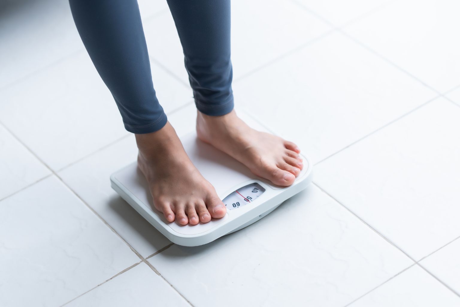 Жінка стоїть на вагах щоб визначити скільки набрала ваги під час вагітності